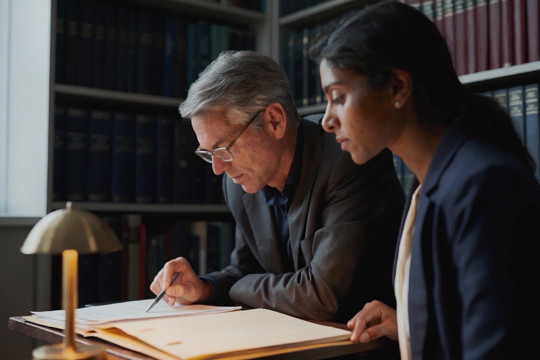 Two colleagues at a table looking over a client file together.